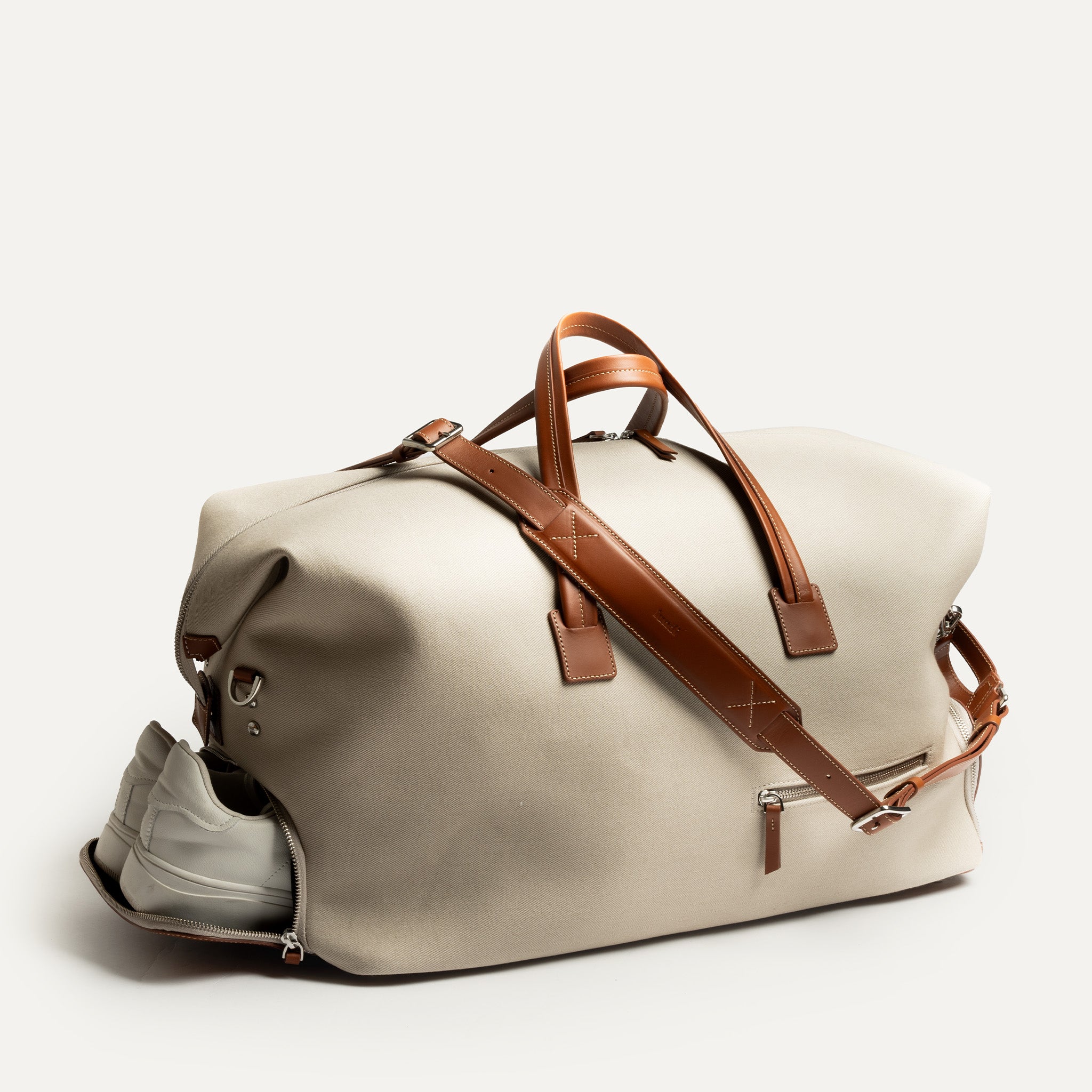 Ce sac de voyage en toile et cuir dispose d'une poche pratique pour les chaussures à part des vêtements pour ne pas les abimer et d'une bandoulière réglable pour un port confortable. Idéal pour les week-ends, il allie durabilité et élégance. 